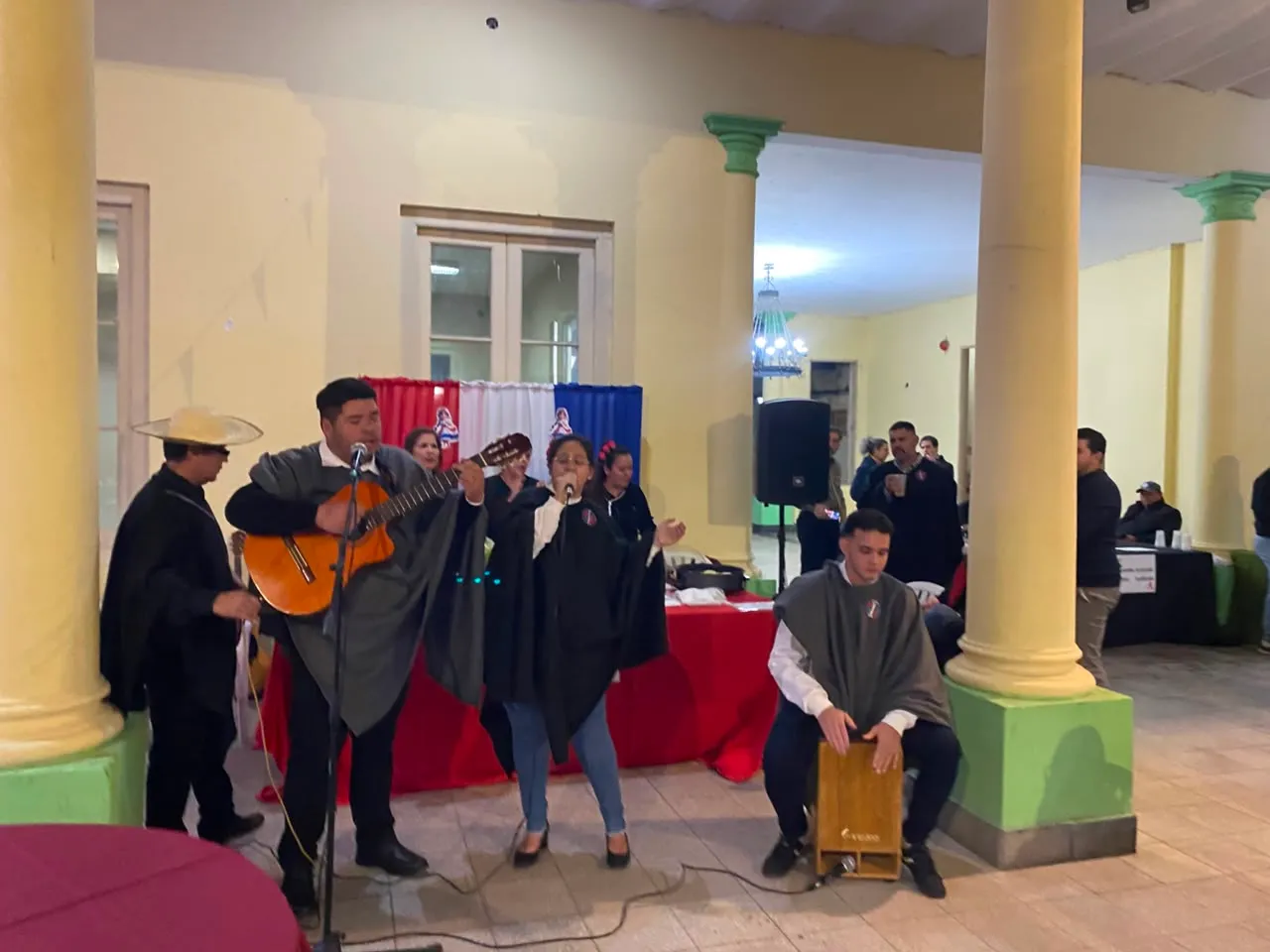 Conjunto musical con guitarra, voz y cajón peruano animando la fiesta en el patio de la sede